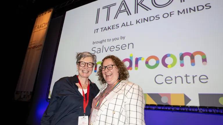 Photo of two ladies standing in front of screen displaying ITAKOM logo and Salvesen Mindroom Centre logo
