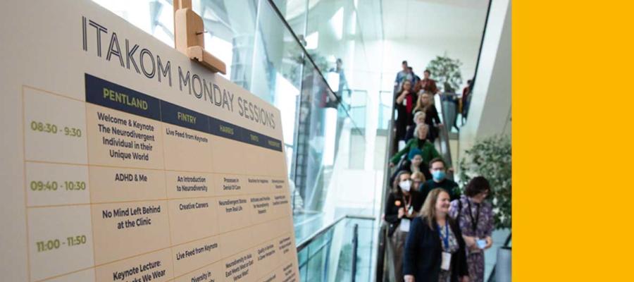 photo of delegates descending on escalator next to conference timetable