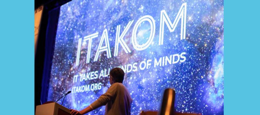 photo of person standing in front of large screen with ITAKOM written on screen