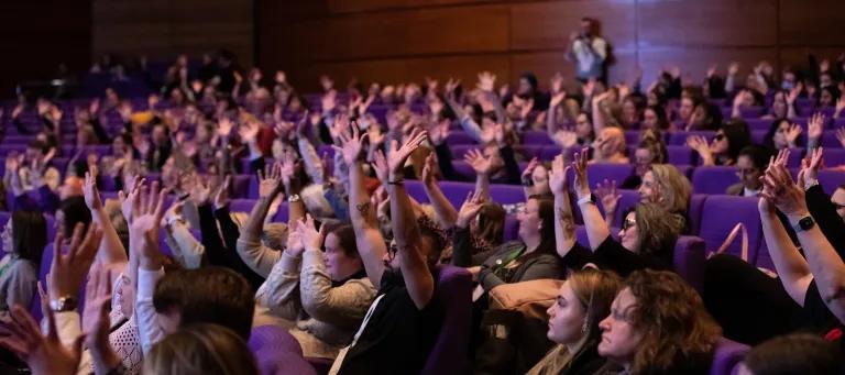 photo of seated delegates waving hands in the air