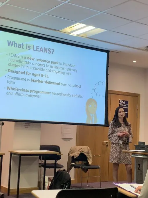 Dr Sarah McGeown standing beside a projector screen giving a presentation