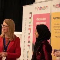 Photo of two ladies smiling in front of posters with information about 'Mindroom'