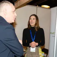 Photo of two people chatting beside a poster with title 'Martin Currie'