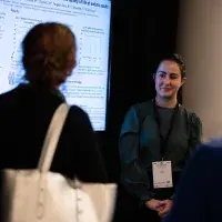 Photo of two people chatting in front of digital poster 