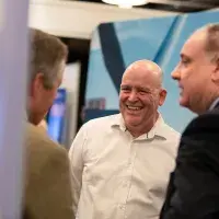 Photo of 3 men standing chatting and smiling