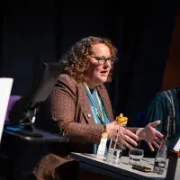 Photo of female speaker seated on panel next to male guest