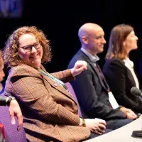 Photo of panel of four people sitting at table with microphone placed on it
