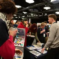 Photo of people chatting at a stall with another person looking at leaflets