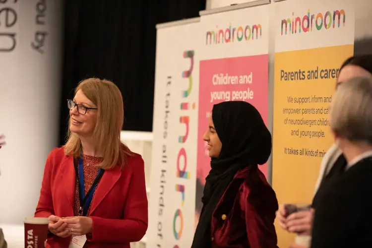 Photo of two ladies smiling in front of posters with information about 'Mindroom'