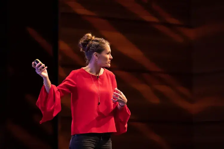 Photo of lady delivering lecture pointing to screen (out of shot)