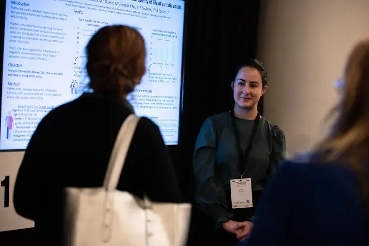 Photo of two people chatting in front of digital poster 