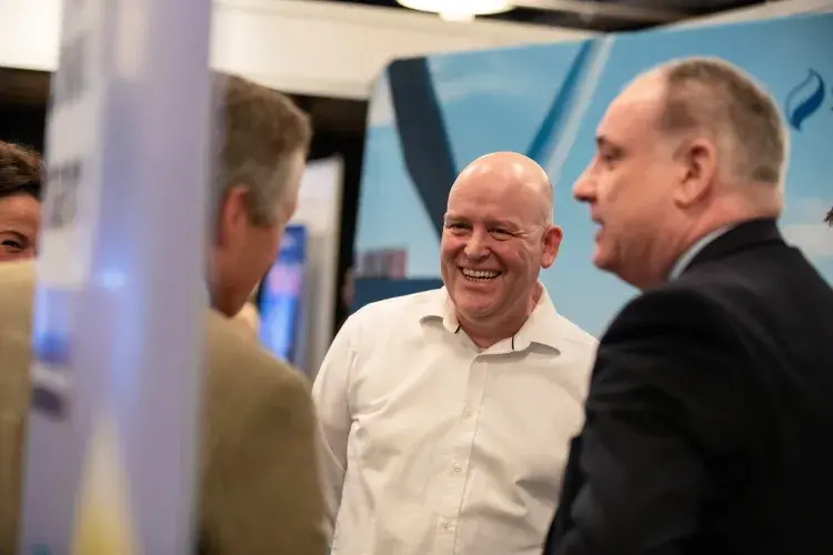 Photo of 3 men standing chatting and smiling