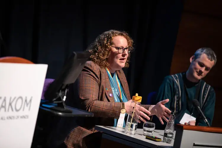 Photo of female speaker seated on panel next to male guest