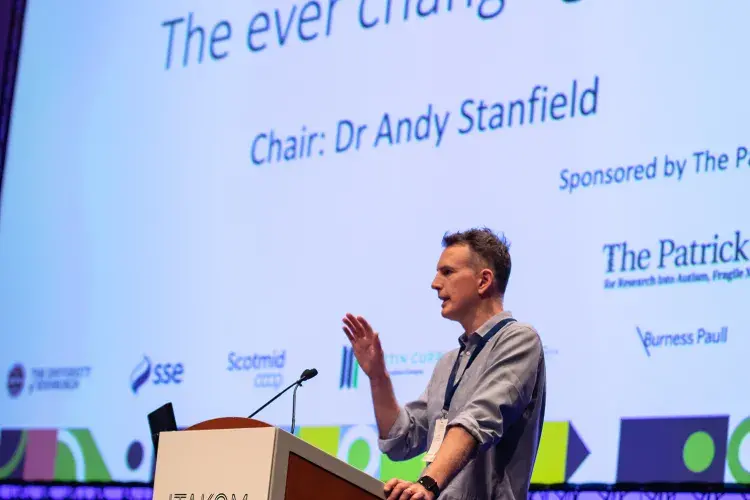 Photo of speaker at lecturn with digital poster behind denoting 'the ever changing brain' title and 'chair: dr andy stanfield'