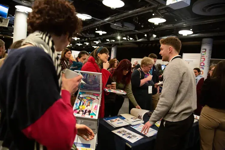 Photo of people chatting at a stall with another person looking at leaflets